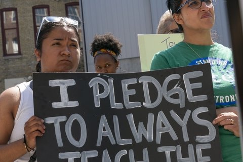 Woman holding sign that reads "I pledge to always teach the truth"