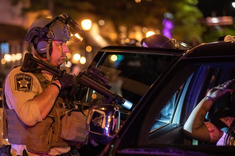 A sheriff pointing a gun at a car.