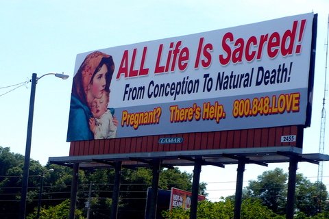 a billboard that says "All life is Sacred! From conception to natural death! Pregnant? There's Help. 800.748.LOVE"