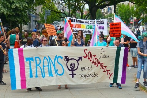 Protesters holding a banner that says Trans Solidarity against transphobia.