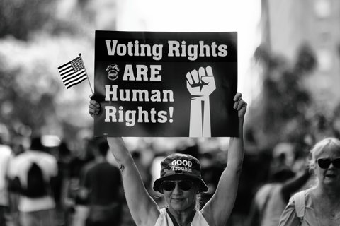 A person holding a banner saying "voting right are human rights!"