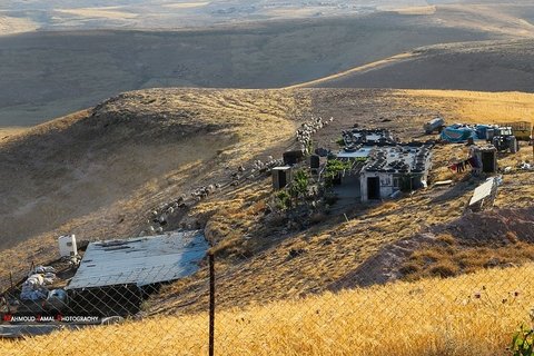 Hills and dunes surrounding houses with tin roofs.