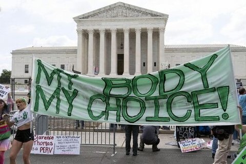 A group of protesters holding a cloth sign saying "my body my choice"