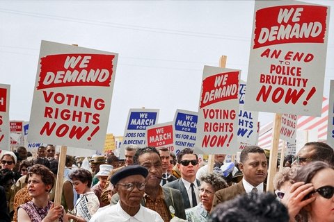 People at a protest holding a sign that says "We Demand Voting rights now!" "We demand An end to police brutality now"