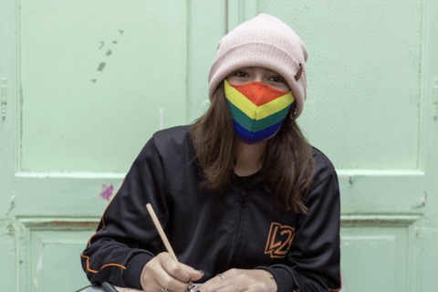 A woman in a pink beanie wearing a rainbow mask.