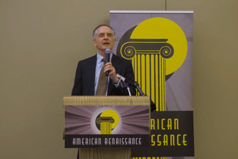 A man behind a podium that says American Renaissance, speaking into a mic.
