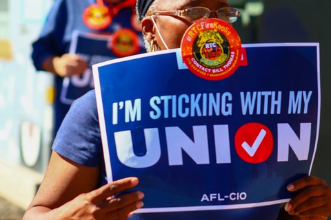 Protestor holding a sign that says, "I'm sticking with my union." Photo by Manny Becerra on Unsplash.