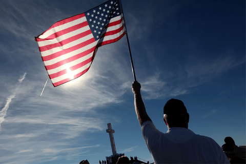 The silhouette of a man holding up an american flag.