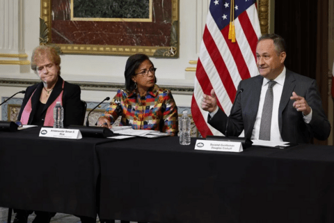 People sitting behind a table with an american flag behind them