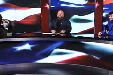 Kanye West in a black mask, Alex Jones, and Nick Fuentes sitting around a desk.