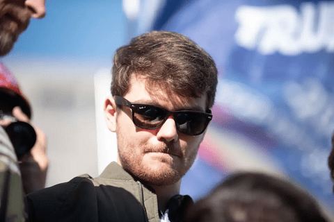 A White man with brown hair wearing sunglasses