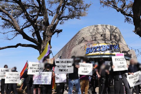 People standing in front of a building, holding signs that say "Fascists go home!"