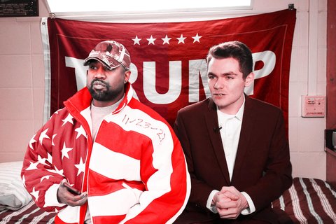 A picture of Kanye West and Nick Fuentes sitting on a bed in front of a Trump flag.