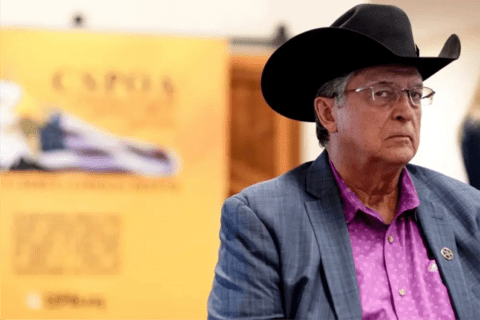 A White man in a ten gallon hat wearing glasses.