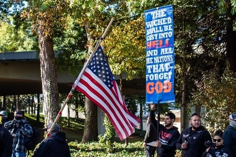 Protesters holding an American flag and protest signs