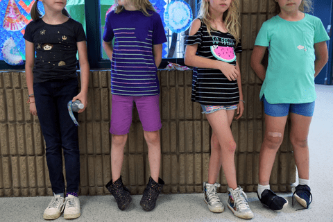 four children leaning against a wall.