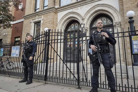 two men in police uniforms standing with guns outside a building that says "Star of Israel"