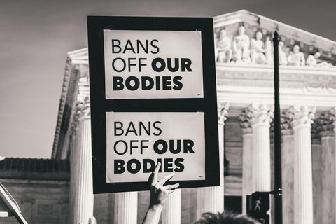 A protestor holding a paper that says "Bans of our bodies"