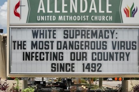 A sign board outside a church that says "white supremacy: the most dangerous virus infecting our country since 1492."