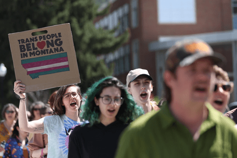 protesters holding a sign saying "Trans people belong in Montana"