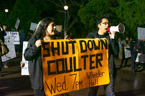 Two students holding a banner that says "Shut down Coulter. Wed 7 PM Wheeler Hall."
