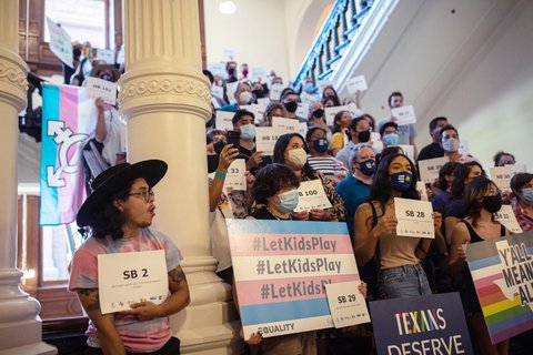 A group of people holding up signs in support of Trans people.