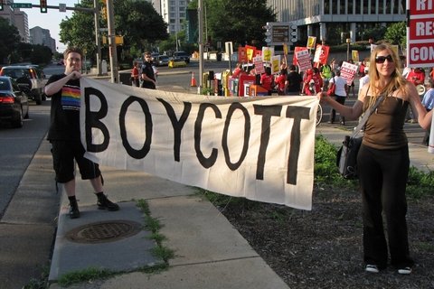 Two people holding a sign that says "Boycott" at a protest