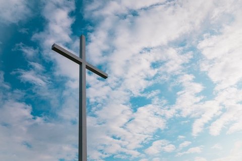a cross with clouds in the background.