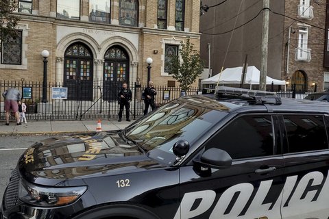 A police car and police men outside a synagogue.