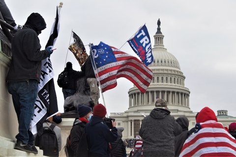 People holding flags of various groups like 2 percenters and Trump flags.