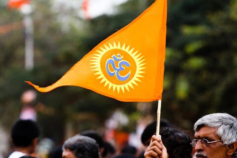 An orange triangle flag with an "Om" on it.