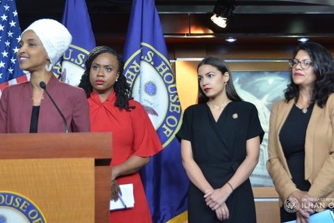 A woman standing in front of a podium with three women behind her.