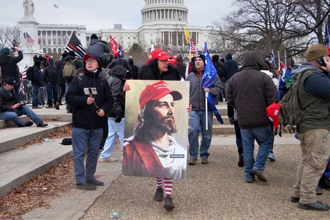 a person in a red maga hat, holding an image of Jesus wearing a maga hat.