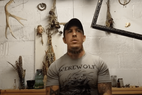 A man in a grey t shirt with hunting memorabilia in the background