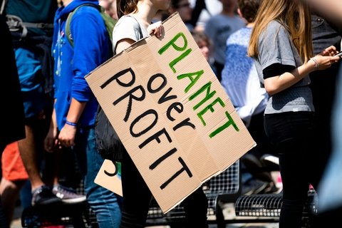 A sign at a protest saying "planet over profit"