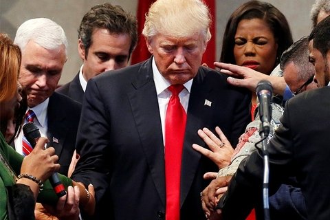 Donald Trump with people in prayer around him.