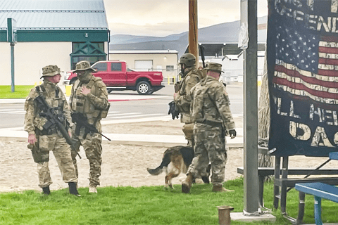Some men in camo standing in the grass.