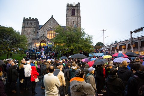 A group of people standing in front of a synagogue with umbrellas open