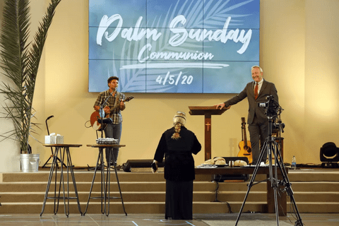 three people on a stage in front of a sign that says "palm sunday communion 4/5/20"