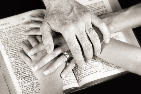 People putting their hands over each other over a book