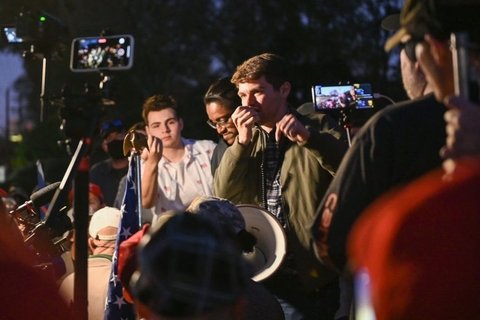 Nick Fuentes speaking into a mic, surrounded by people