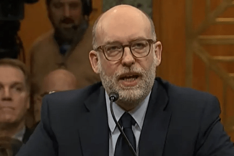 A man in glasses wearing a suit.
