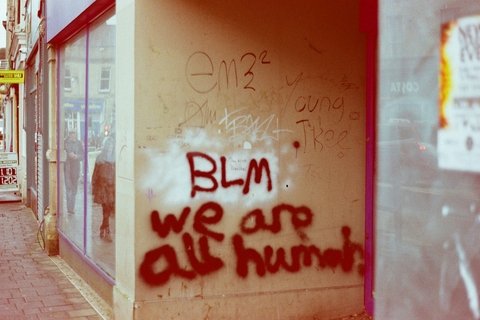 An image of a pillar with graffiti that says "BLM We are All Human"