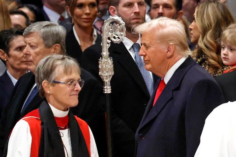 A woman in bishop's clothing talking to a man in a suit.