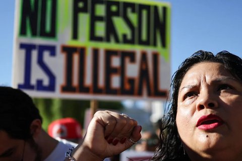 A protestor holding a sign that reads "No person is illegal"