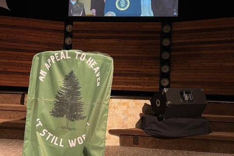 an image with an appeal to heaven flag before a screen showing President Trump