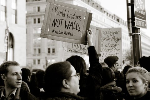 A protestor holding a sign that says "build bridges not walls"