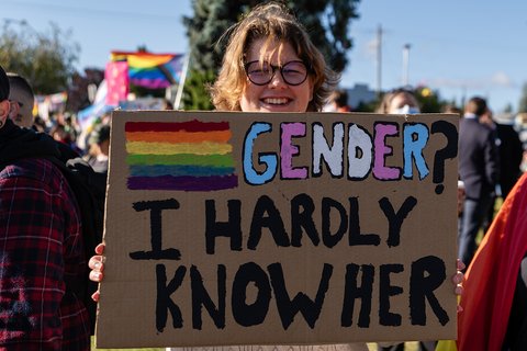 A sign at a protests saying "Gender? I hardly know her"