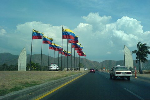 Venezuelan flags along a road with cars on it