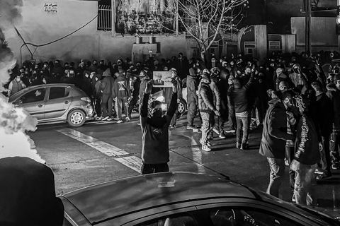 A man standing in the street in a protest holding a sign